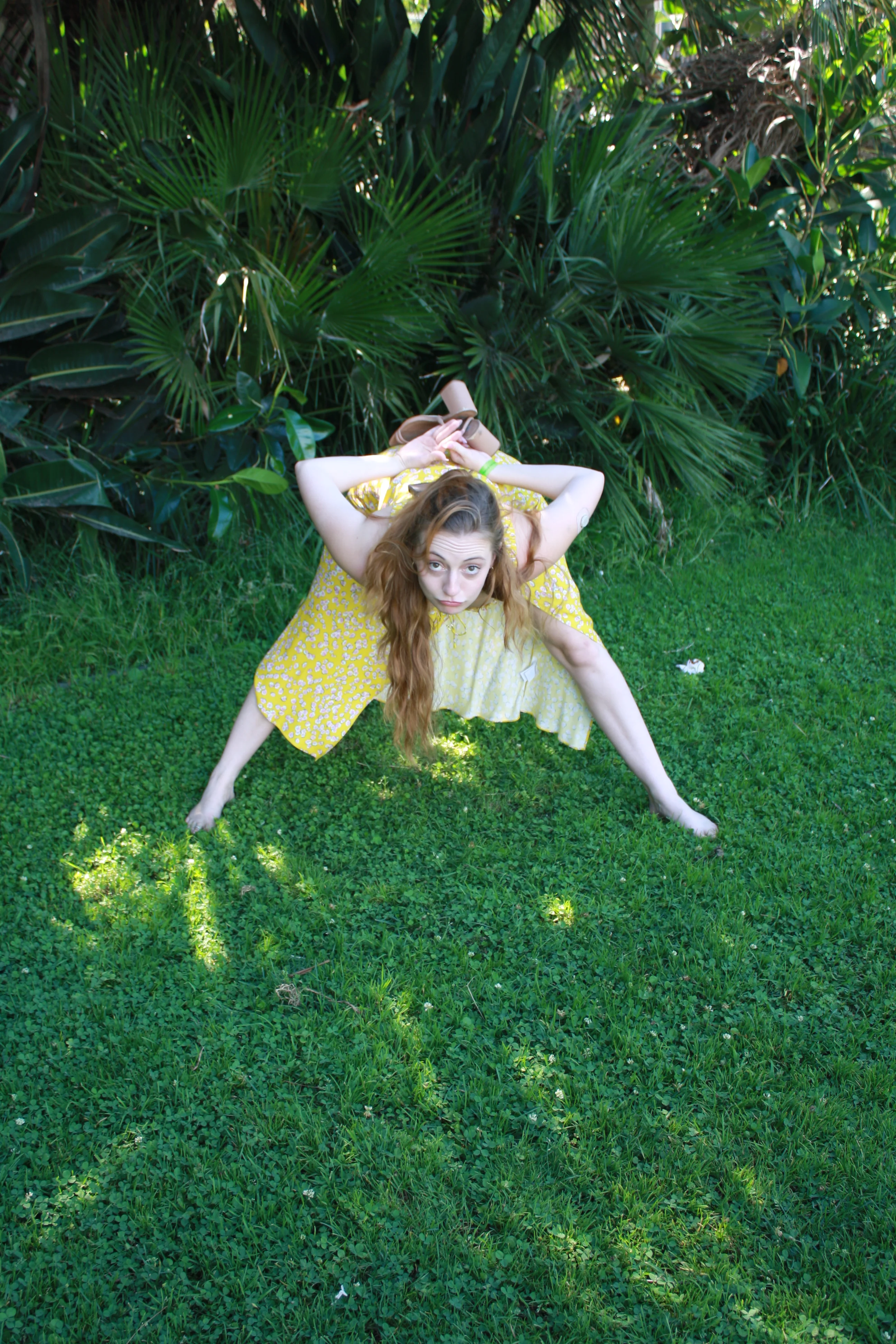 Jordie Morris bending forward with feet wide apart and shoes held overhead at the Exposition Park Rose Garden.